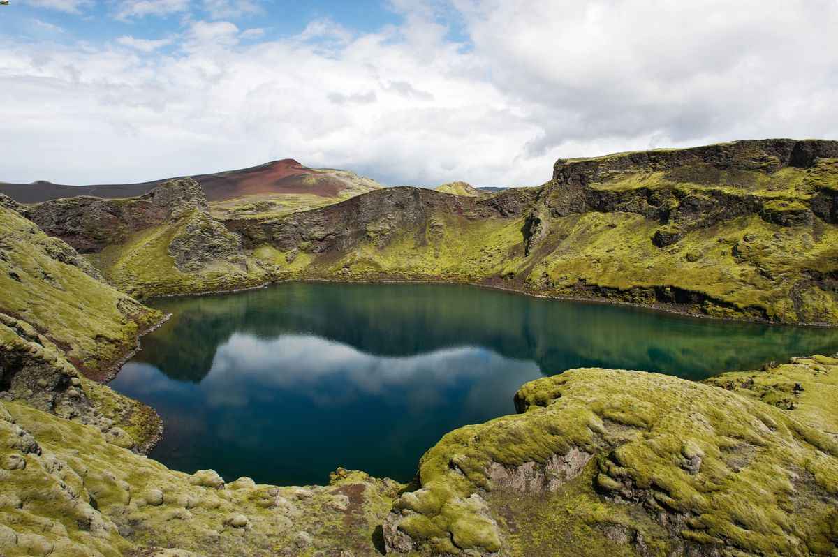 Deep blue crater lake surrounded by mossy lava near Laki.