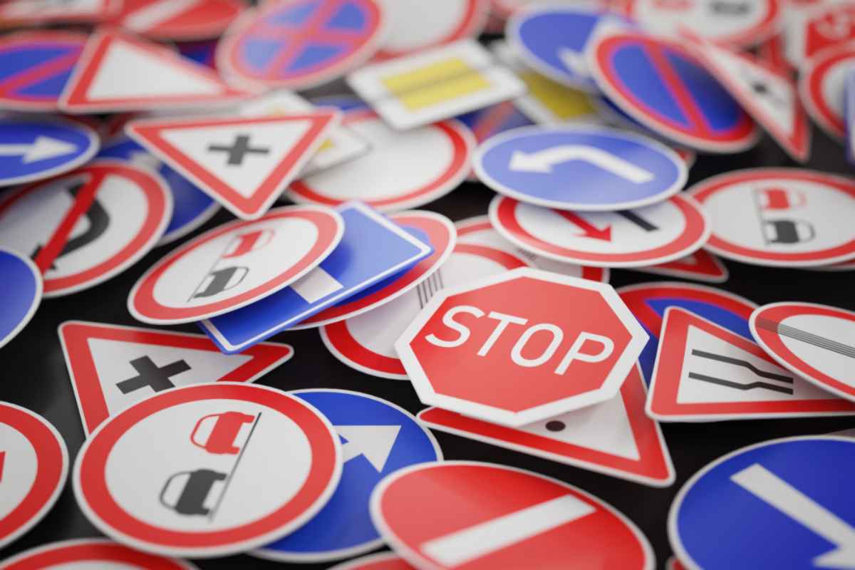 Pile of European traffic signs including STOP, no passing, and turn arrows.