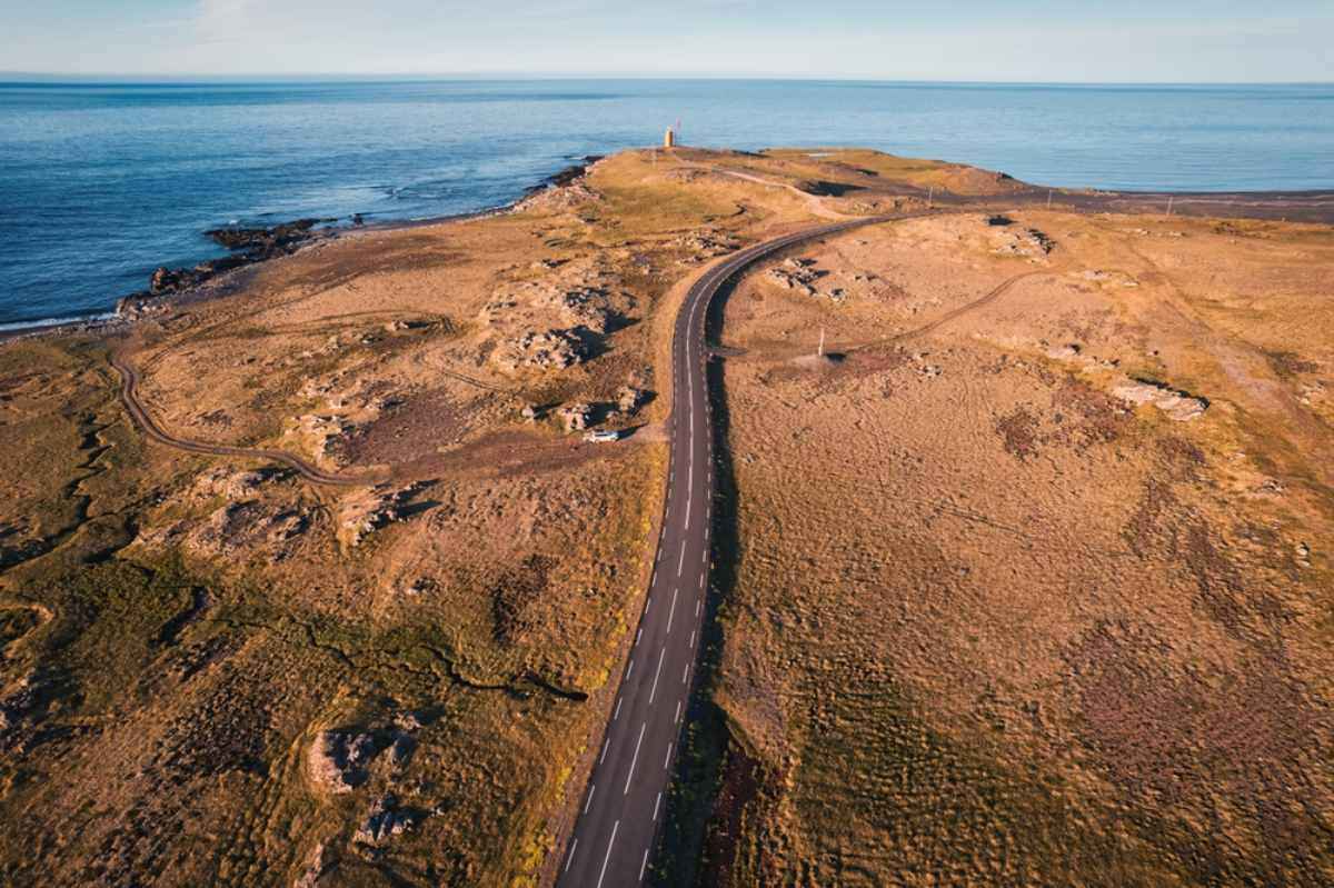 Aerial view of a coastal road winding along a rocky Icelandic peninsula.
