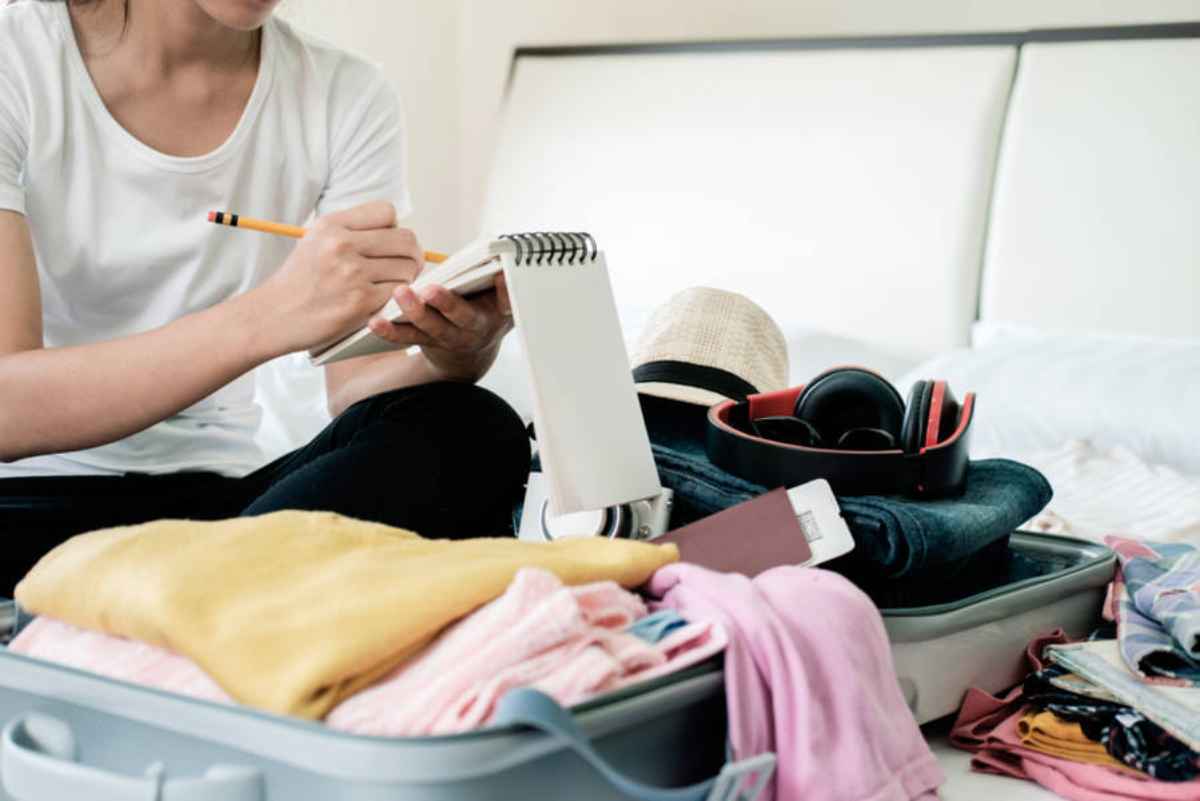 Traveler writing a packing checklist next to an open suitcase for an Iceland Highlands trip.