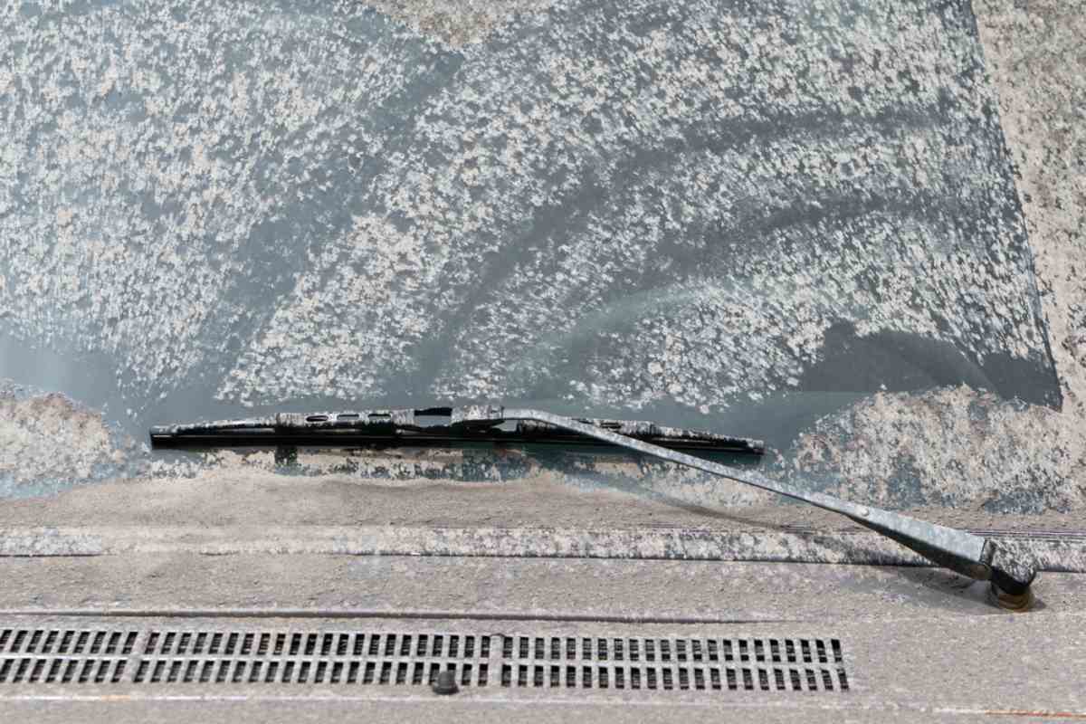 Windshield coated in volcanic ash and grit with a damaged wiper blade.