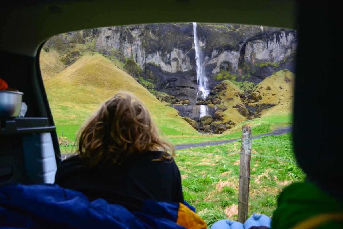 A person with long hair enjoys the nature print left by a waterfall while staying inside a camper.