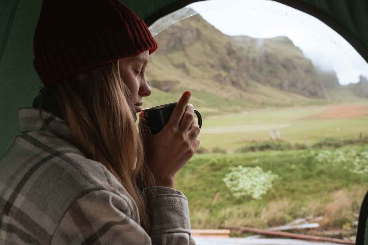 A hiker enjoys a well-deserved cup of coffee after making camp in a permitted area of Iceland for the night.