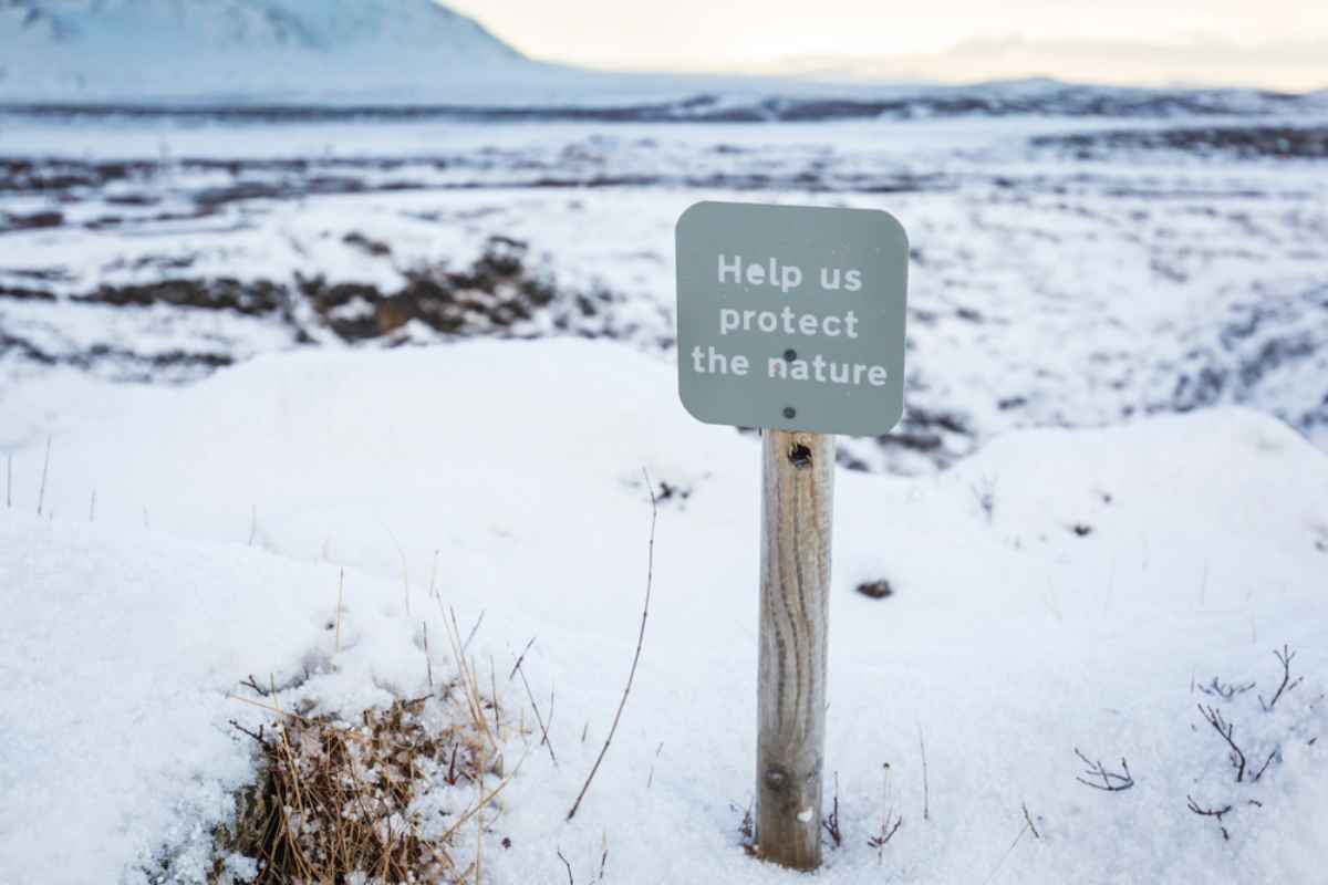 A sign informs about the need to protect nature in a completely snowy Icelandic landscape.