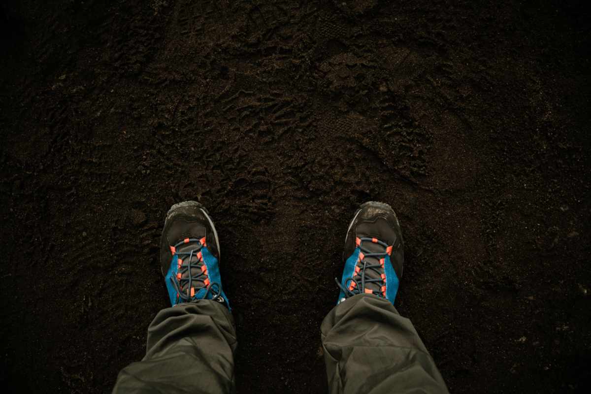 Point-of-view of sturdy hiking boots standing on black volcanic sand, ready for trails.