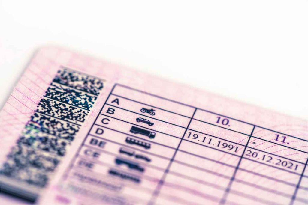 A close-up photo of a driver’s license showing license categories and expiration dates, with a QR code visible on the left side.