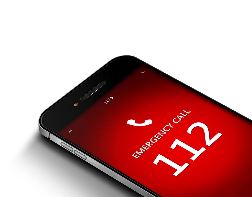 Close-up of a smartphone screen showing an emergency call to 112, with a red background and a white phone icon.