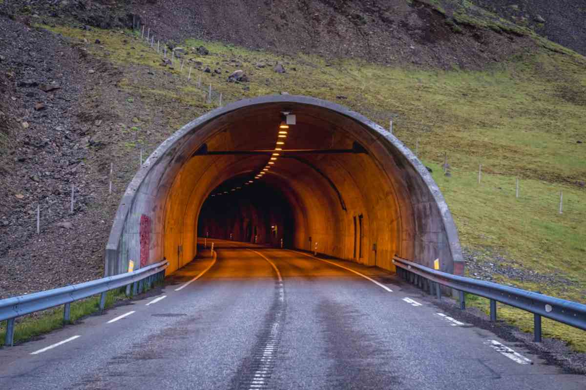 Entrance to Almannaskarðsgöng tunnel glowing amber on a mountain road in East Iceland.
