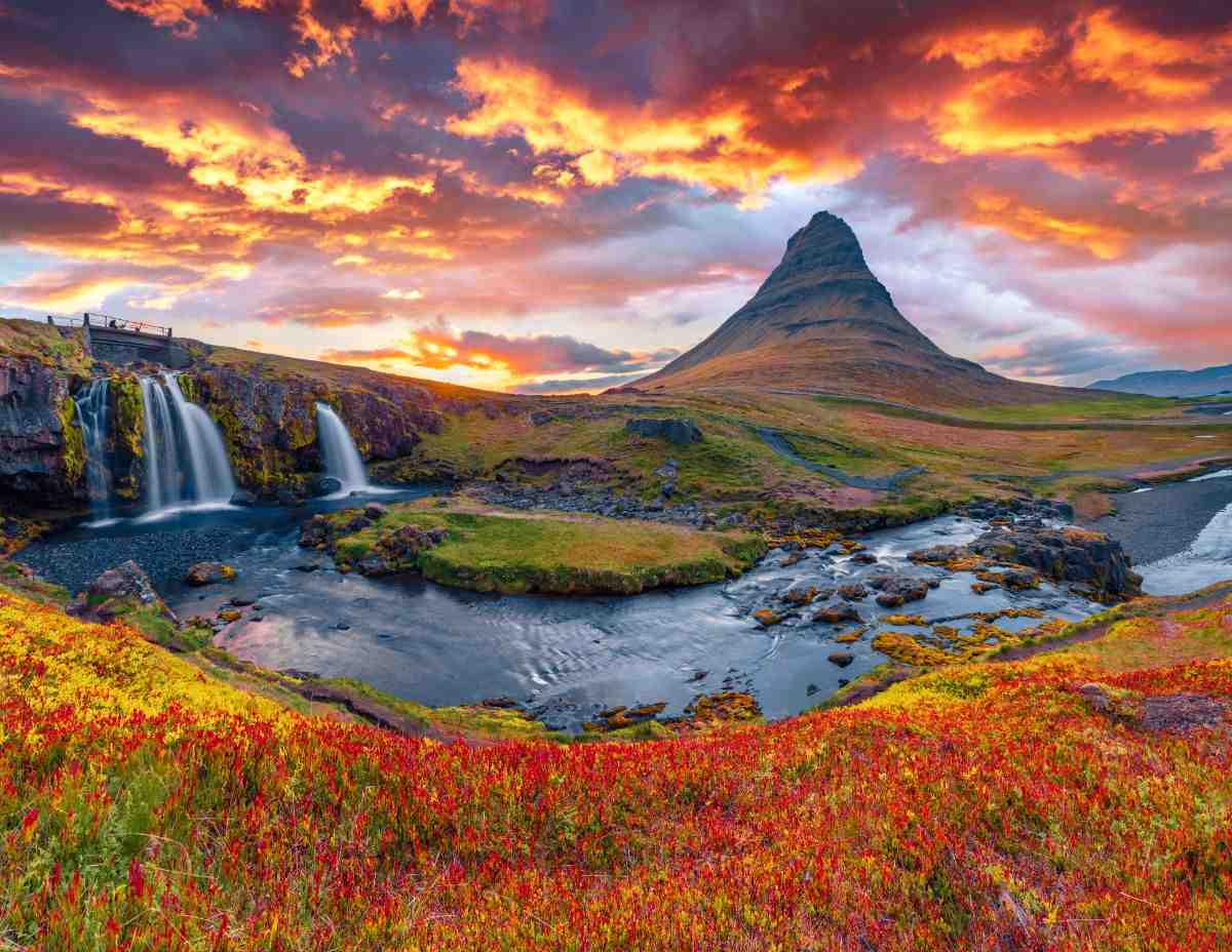 Kirkjufell and Kirkjufellsfoss at a fiery August sunset, red tundra in the foreground and glowing clouds over Sn&aelig;fellsnes Peninsula, Iceland.
