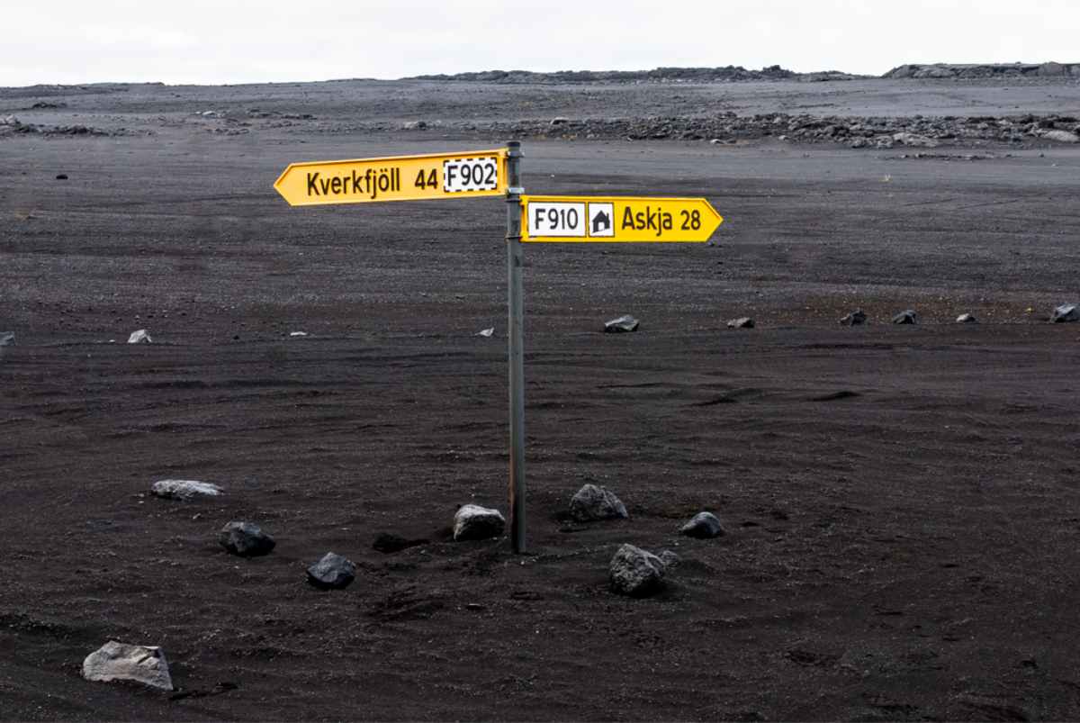Yellow signposts labeled “F902” and “F910” in a black volcanic landscape; highland F-roads.