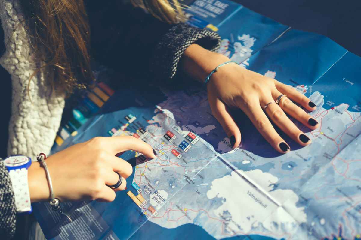 Close-up of hands planning a route on a detailed road map of Iceland.