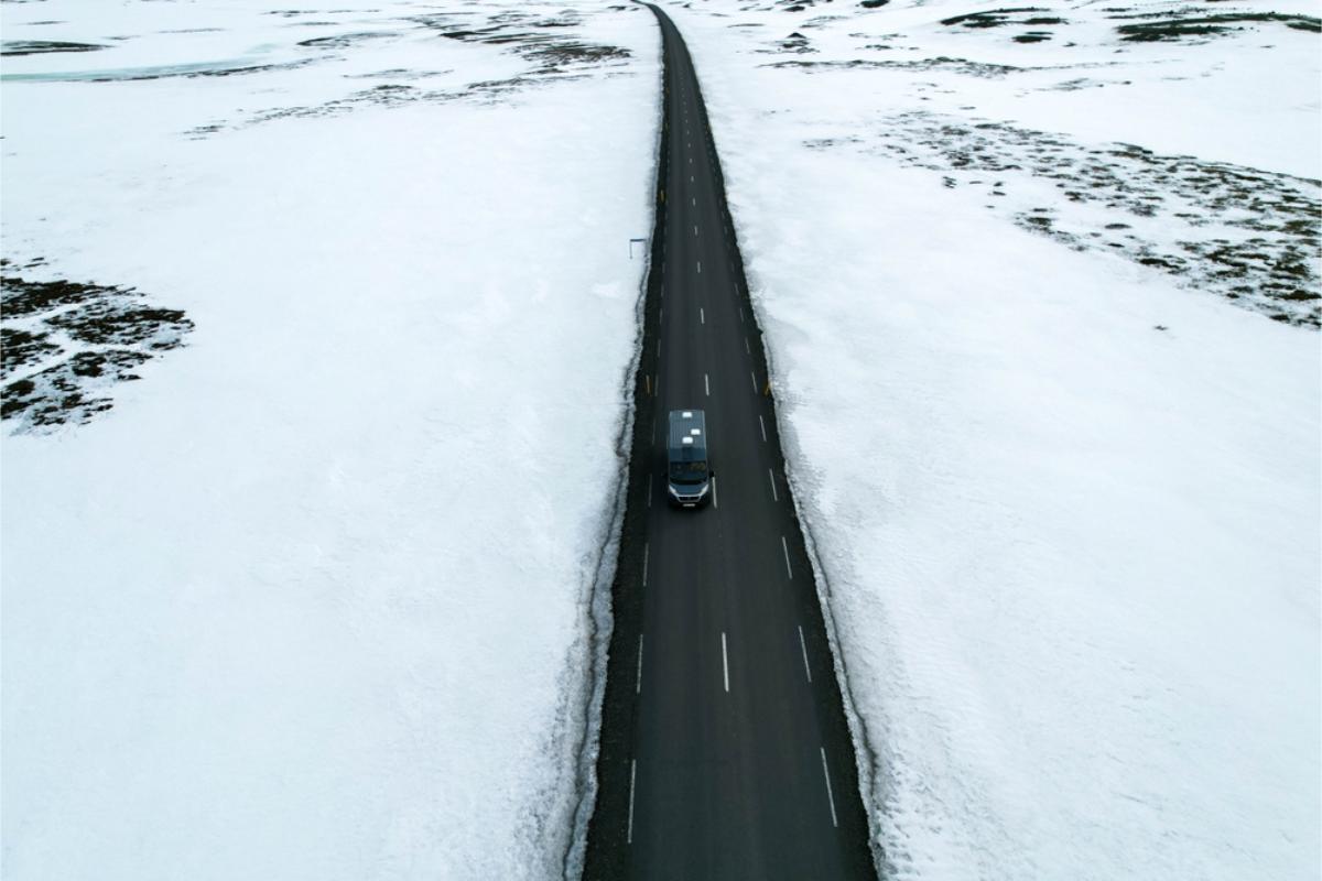 Camper rollong on a clear road while the surrounds are covered in snow