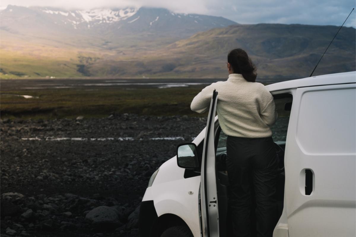 woman hanging onto the door of her camper while watching the impressive landscape