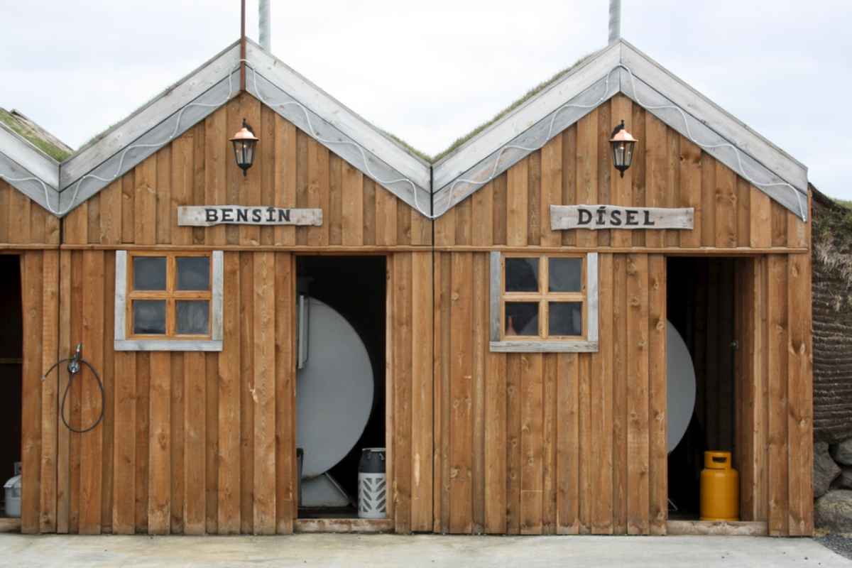 Rustic Icelandic gas station with wooden huts labeled “BENS&Iacute;N” and “D&Iacute;SEL.”