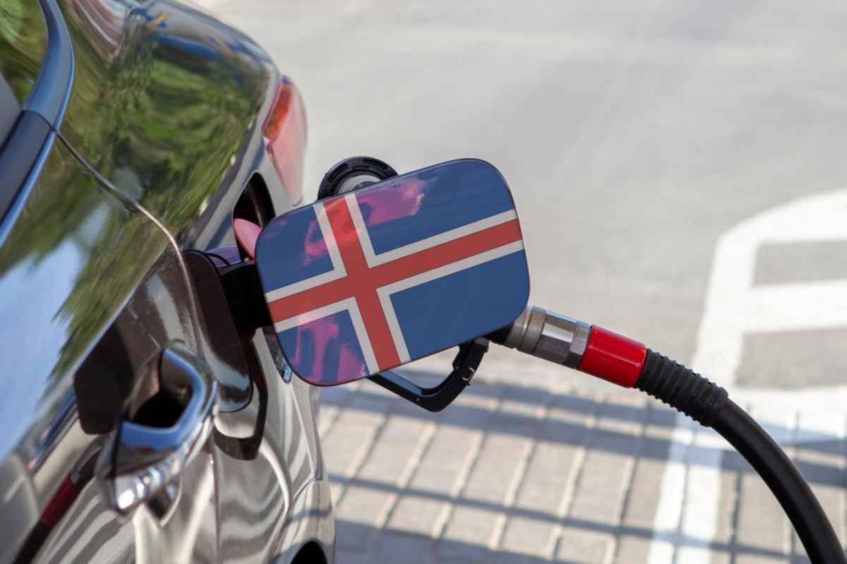 Car refueling; nozzle inserted and fuel door painted with the Icelandic flag.